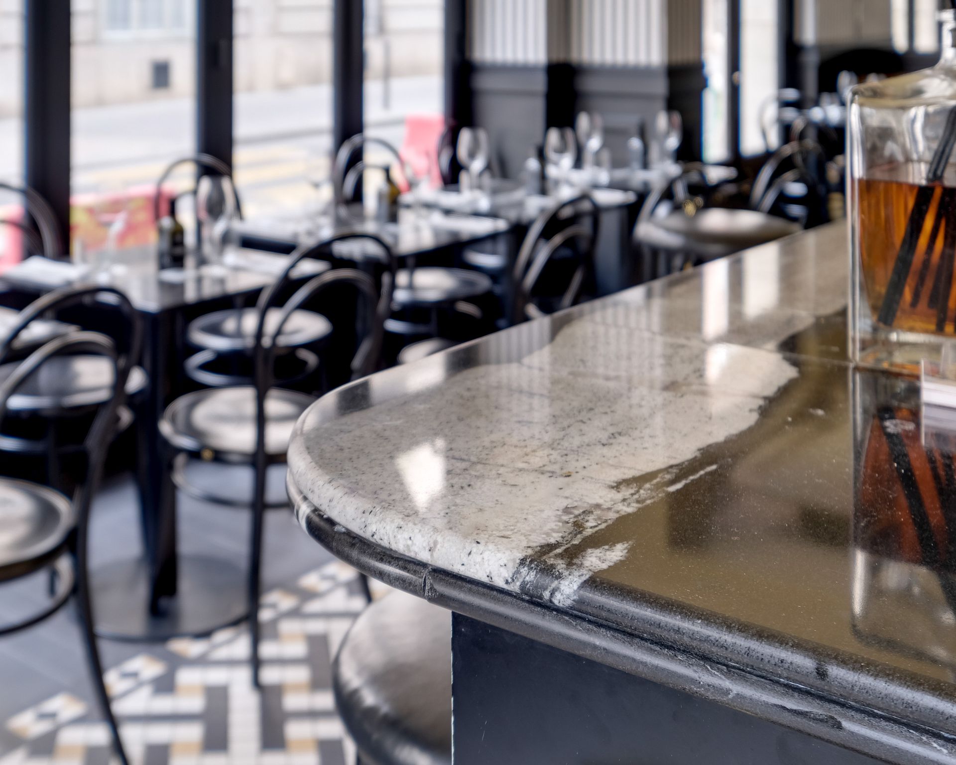 Comptoir de bar gris clair moucheté en granit sur toute sa longueur, soubassement noir