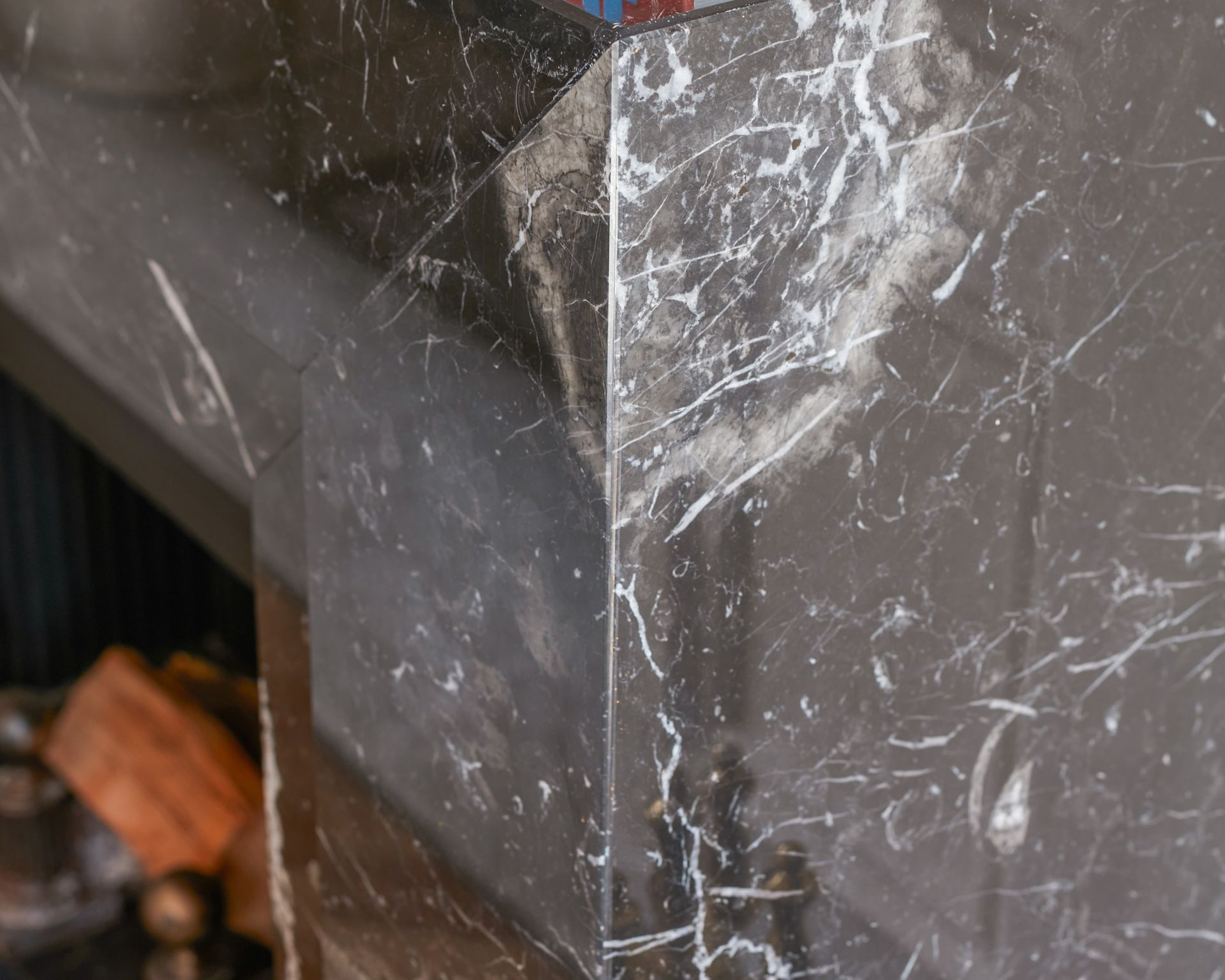 Détail d'un habillage de cheminée noir en marbre Noir Marquina, à manteau droit
