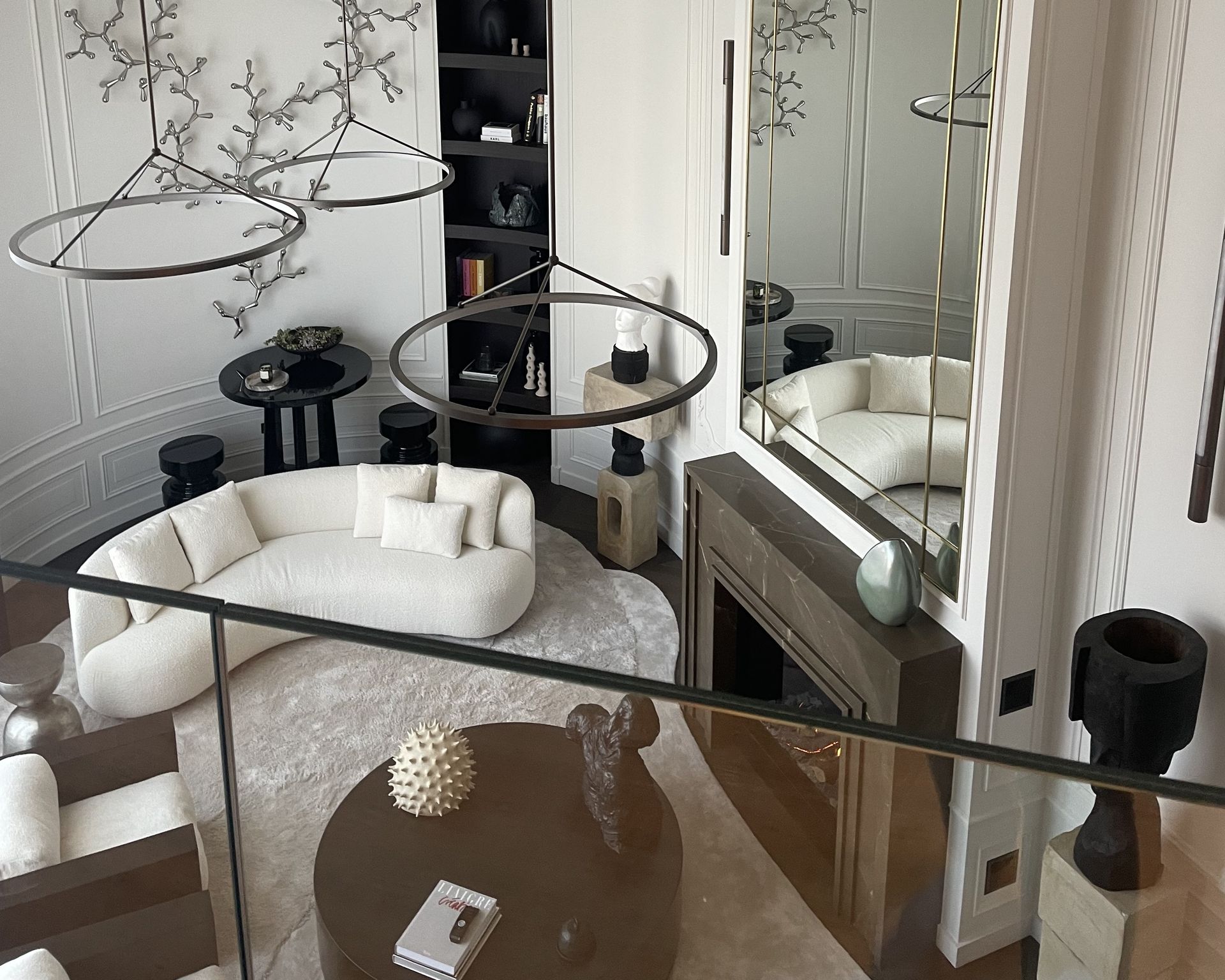 Cheminée habillée de marbre Pietra Grey gris brun vue depuis un salon à boiseries blanches