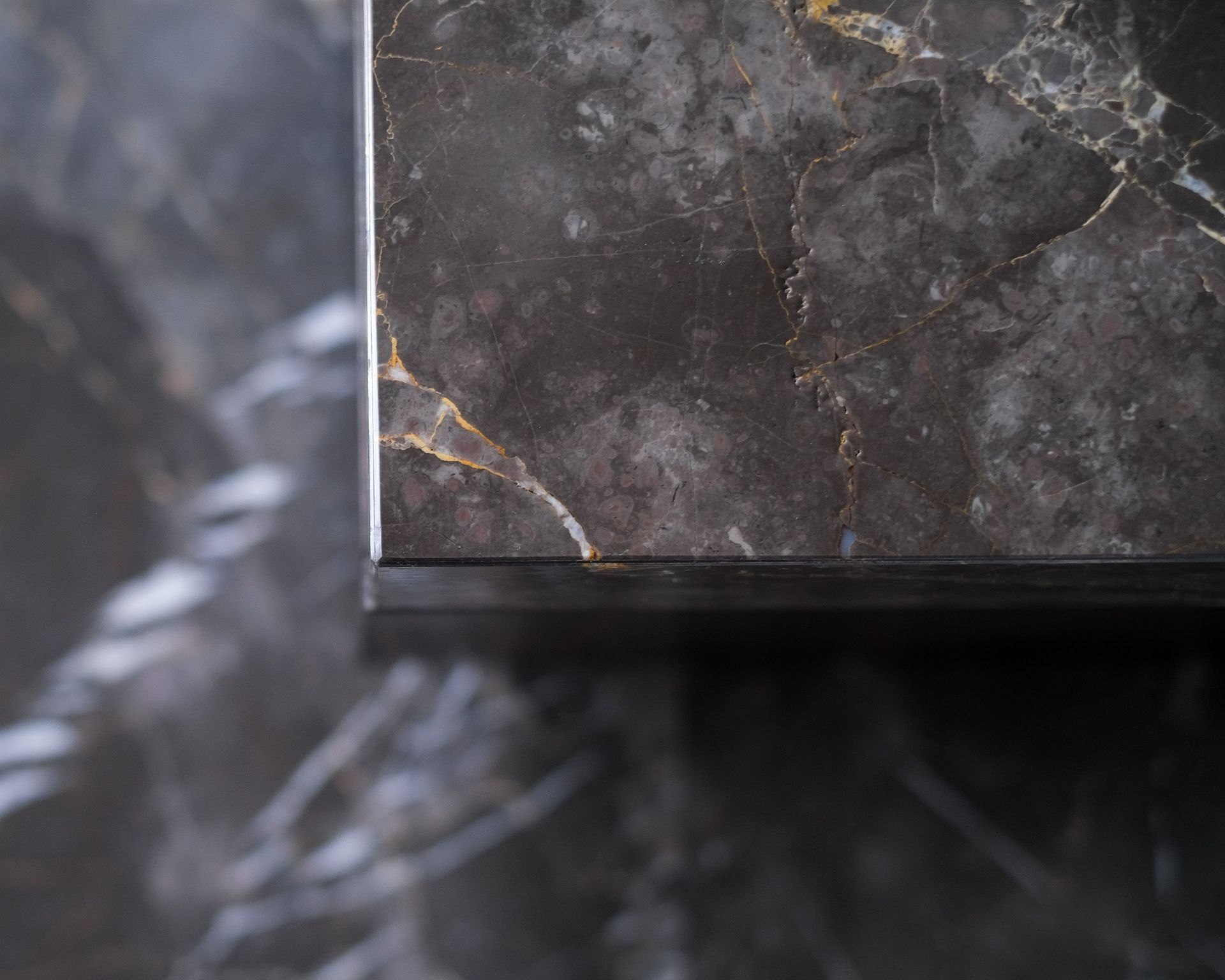 Gros plan d'un plan de travail gris en marbre Grigio Collemandina, cuisine à façades bois foncé, Studio Carrez