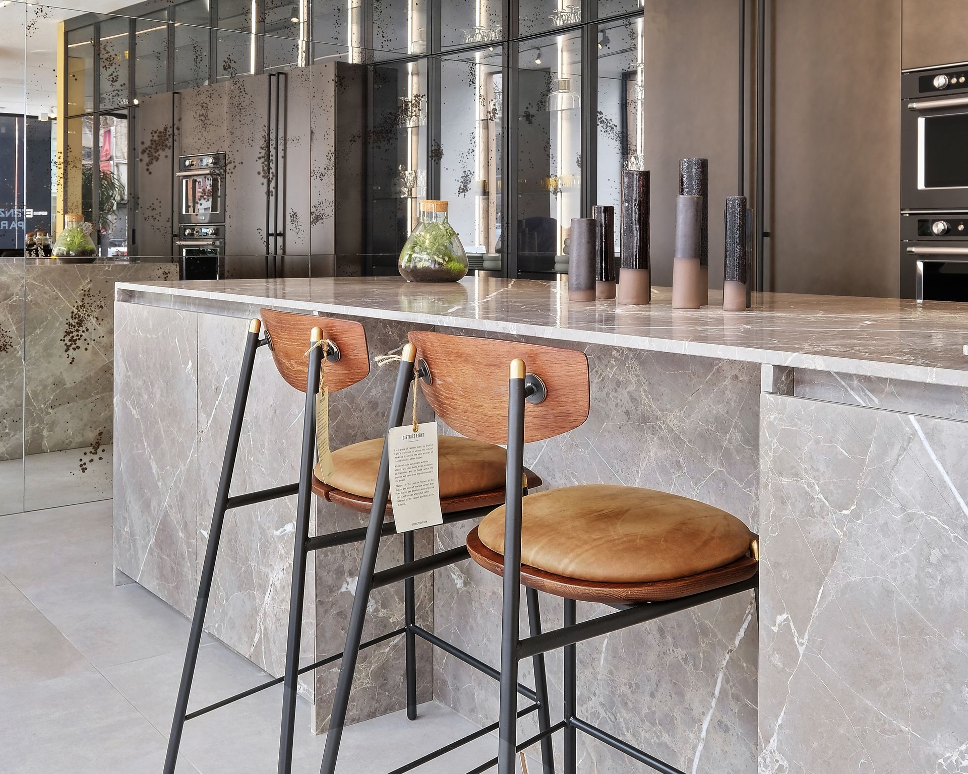 Îlot de showroom à plan de travail gris en marbre Grigio Collemandina et tabourets bois
