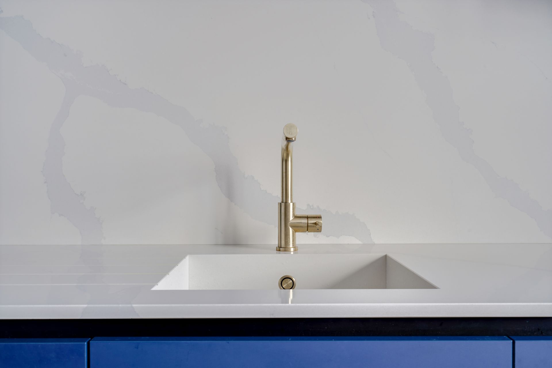 Évier taillé dans un plan de travail blanc en quartz Silestone Eternal Calacatta Gold, cuisine à façades bleues