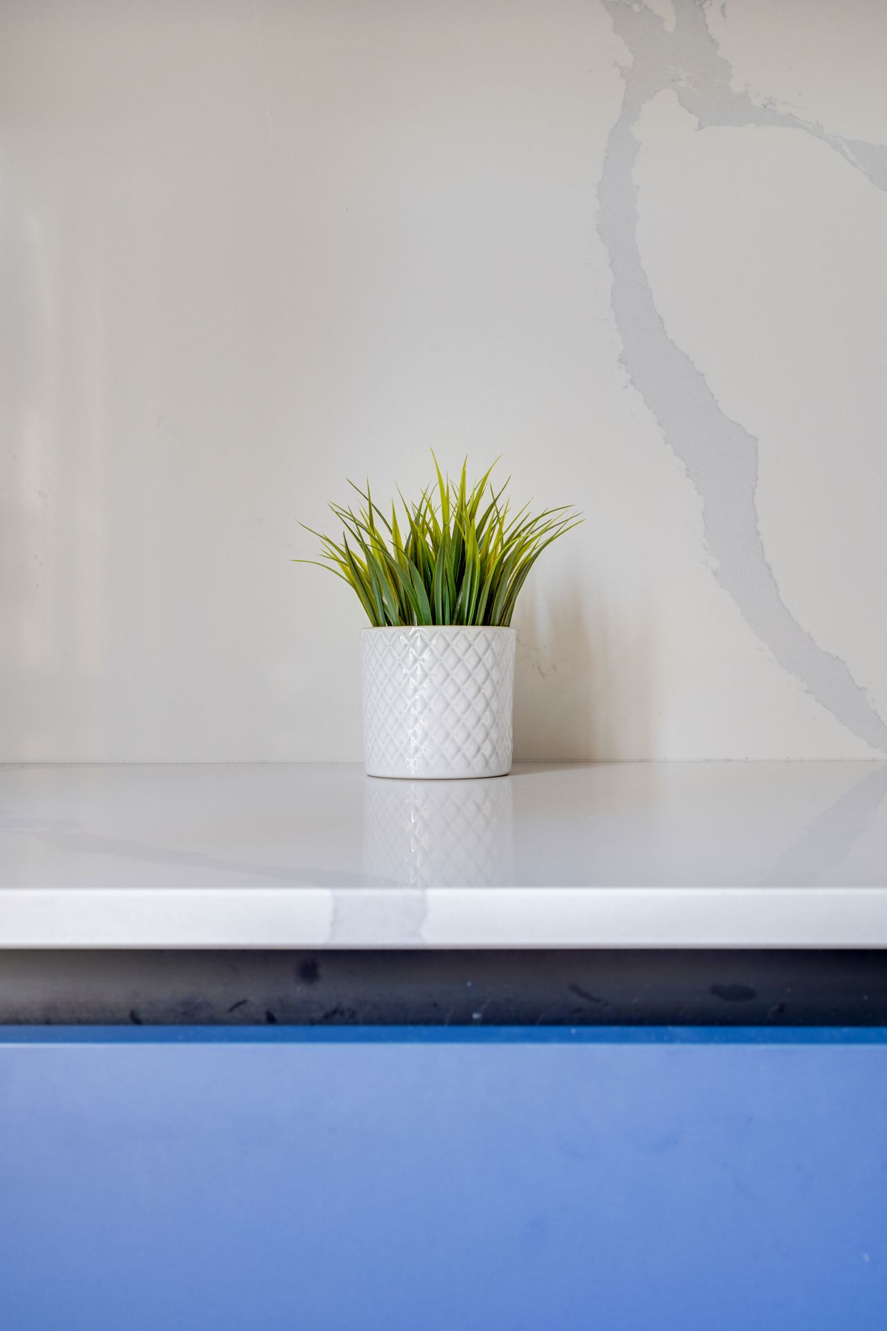 Angle d'un plan de travail blanc en quartz Silestone Eternal Calacatta Gold, cuisine à façades bleues