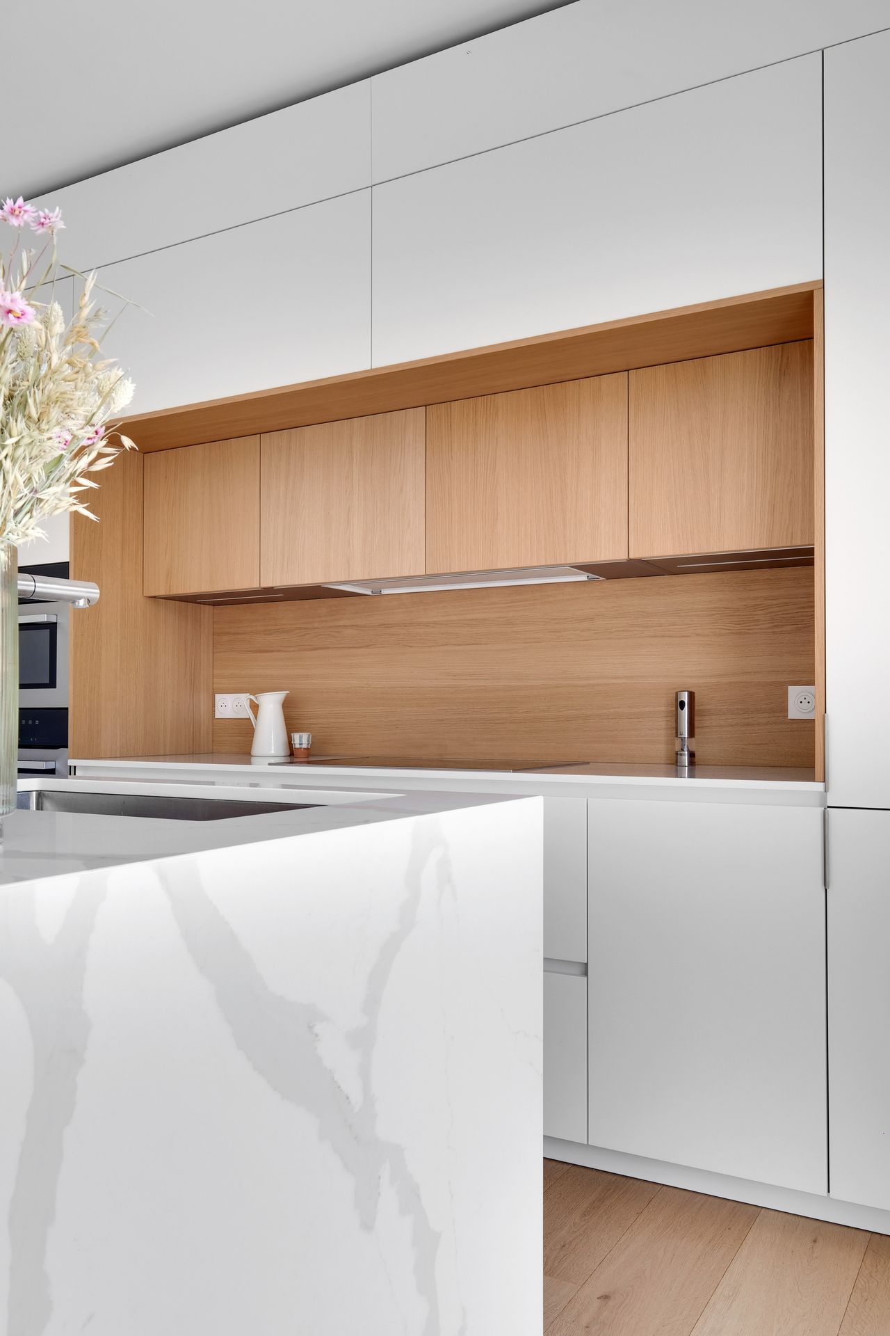 Îlot de cuisine à façades blanches et bois clair, plan de travail blanc en quartz Silestone Calacatta Gold