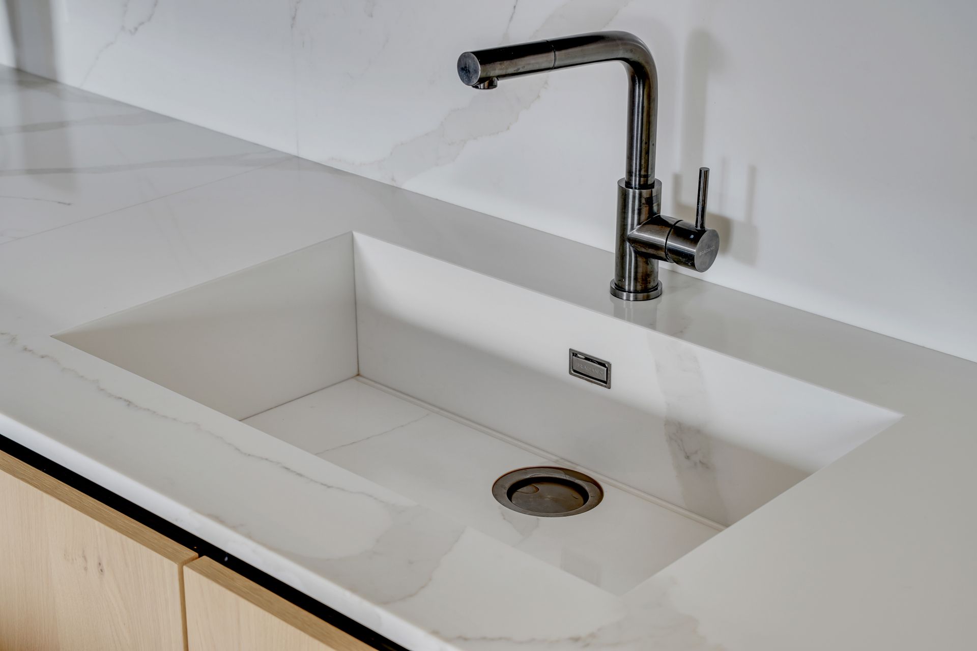 Évier taillé dans un plan de travail blanc en quartz Silestone Calacatta Gold, cuisine à façades bois clair et anthracite