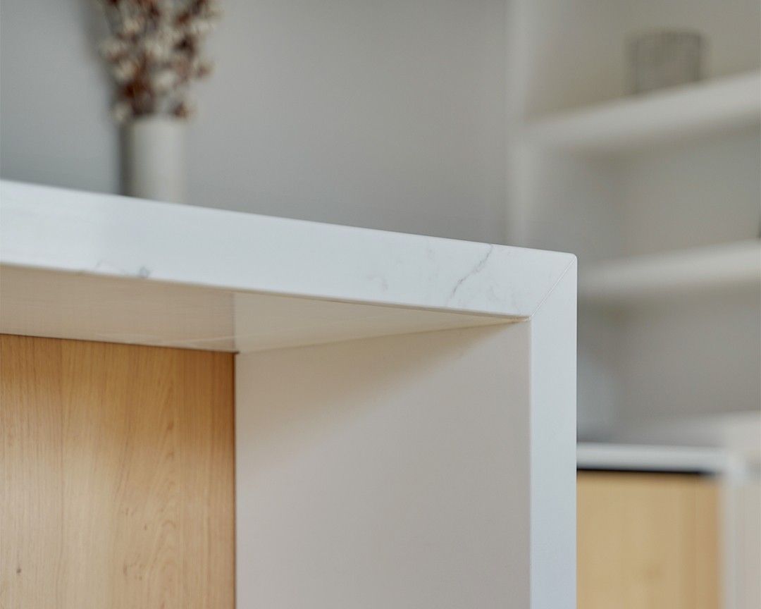 Angle d'un plan de travail blanc en quartz Silestone Calacatta Gold, cuisine à façades bois clair et anthracite