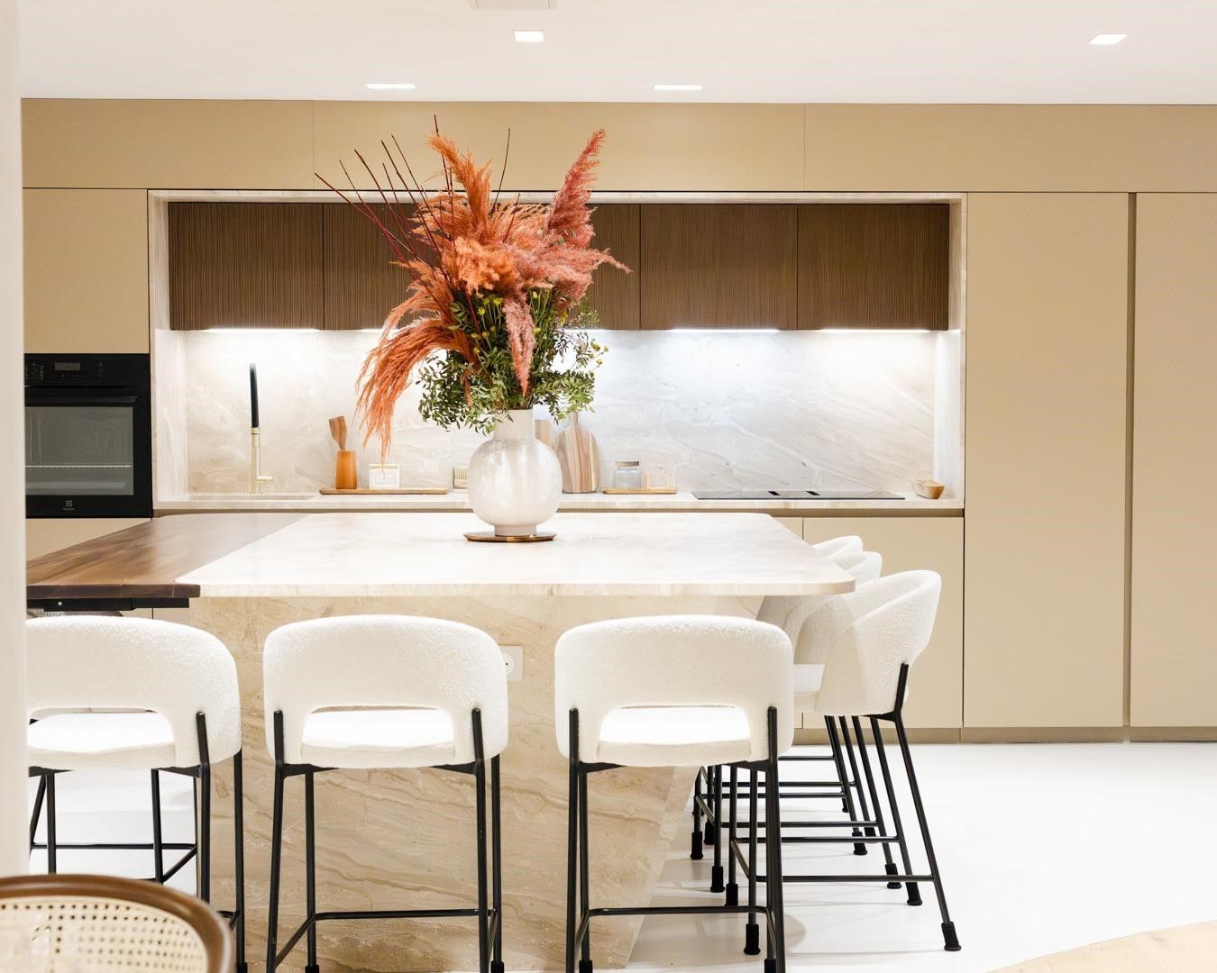 Cuisine à façades beige sable et bois foncé, plan de travail crème en marbre Breccia Sarda