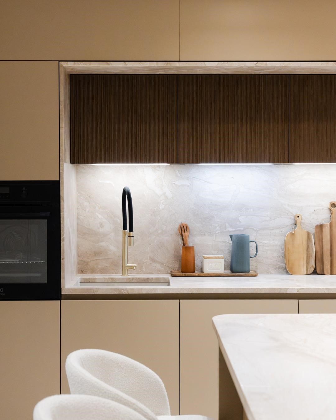 Plan de travail et crédence crème en marbre Breccia Sarda, cuisine à façades beige sable et bois foncé