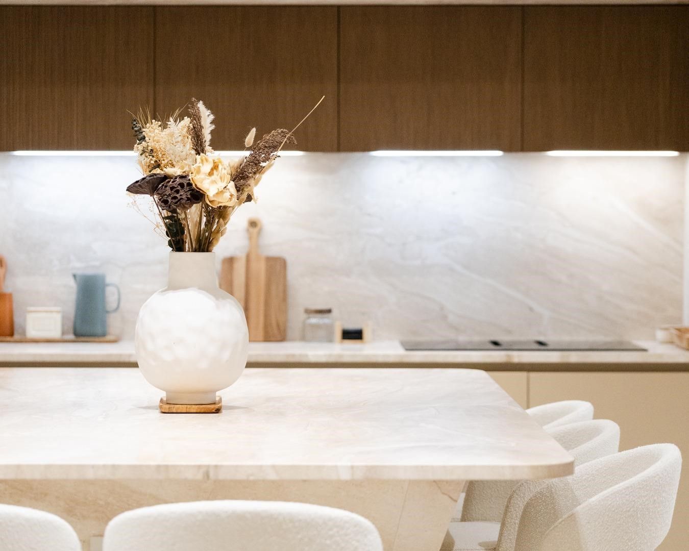 Îlot de cuisine à façades beige sable et bois foncé, plan de travail crème en marbre Breccia Sarda