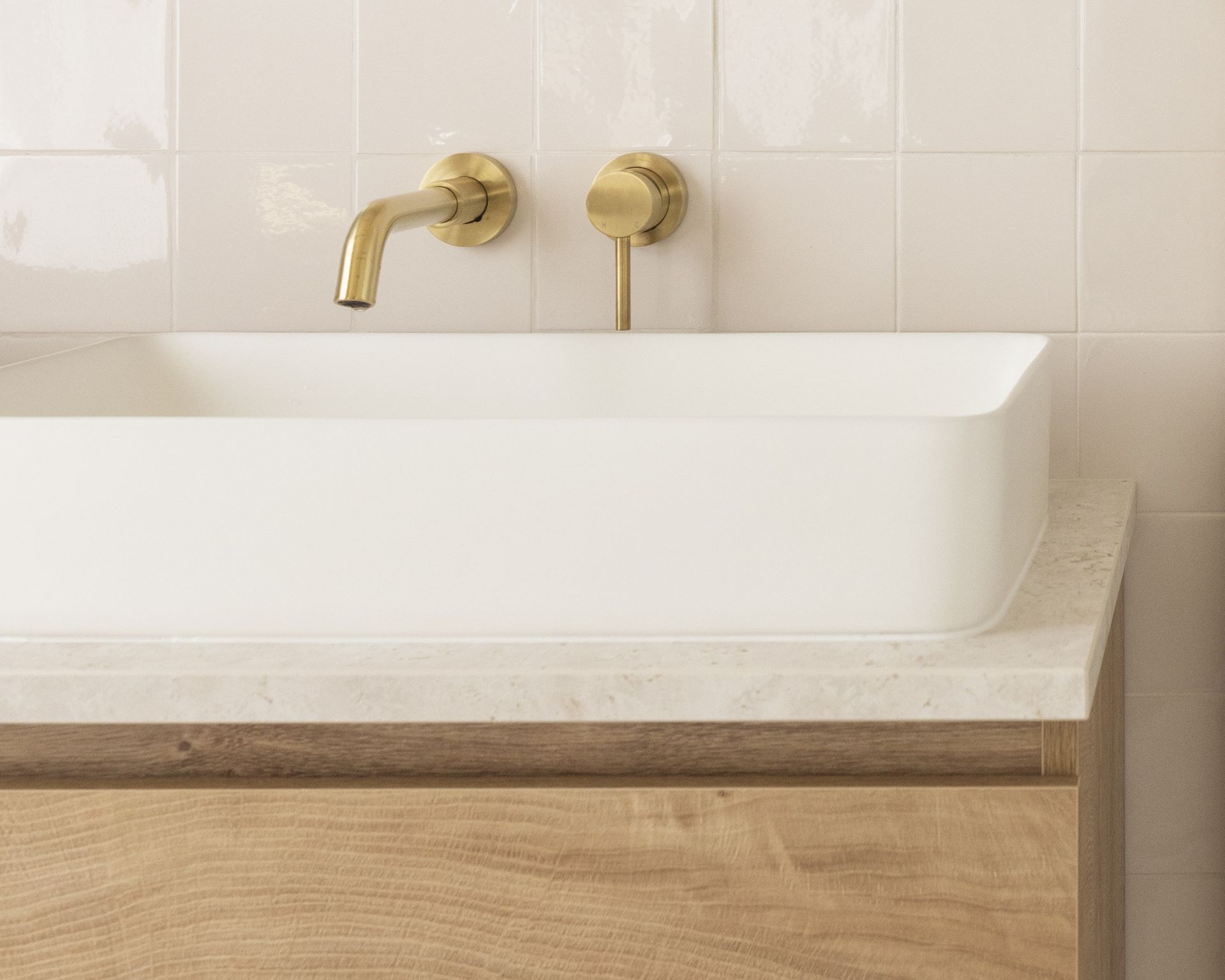 Plan de vasque beige en pierre naturelle sur un meuble bois clair, Karen Tinka