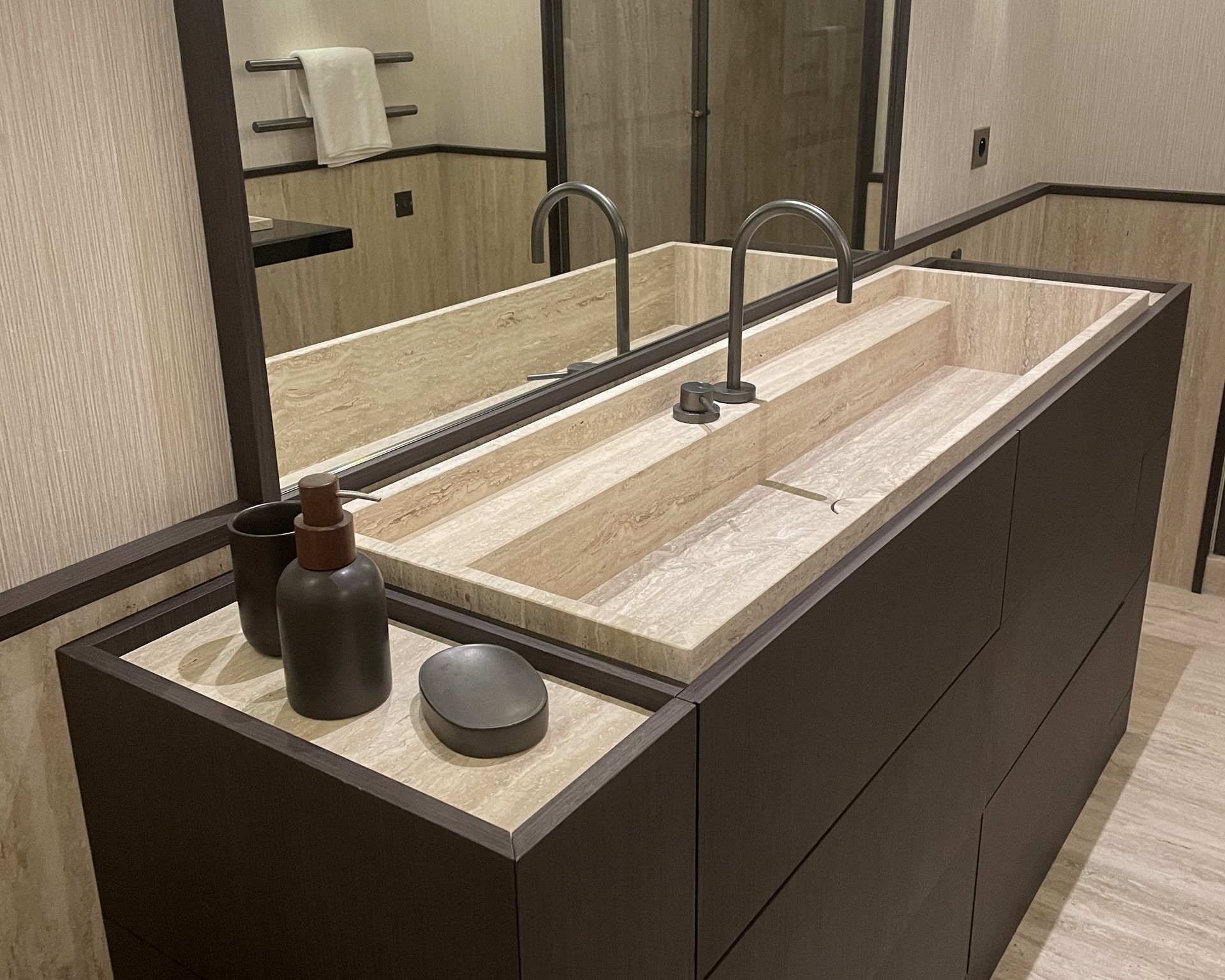 Plan de double vasque beige en travertin sur un meuble brun foncé