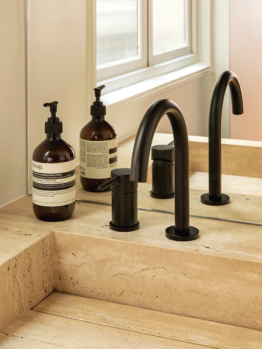 Gros plan du travertin beige dans une salle de bains à meuble bois foncé