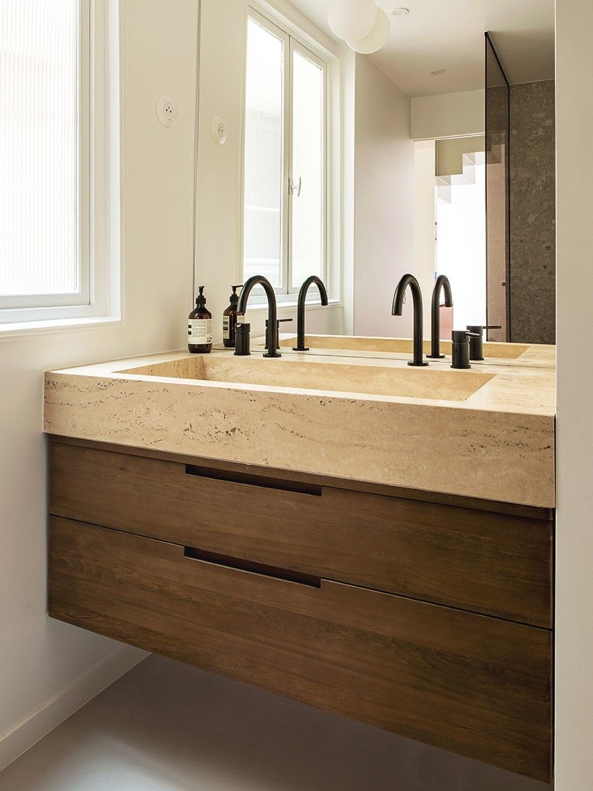 Plan de vasque beige en travertin sur un meuble bois foncé