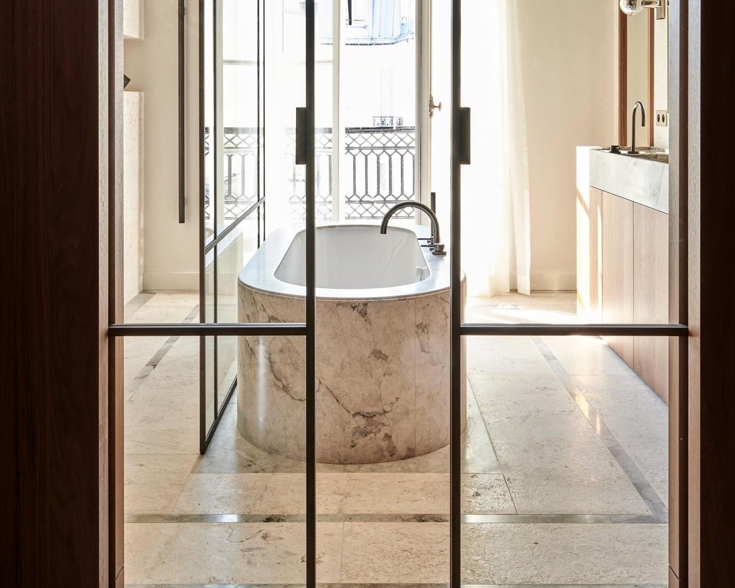 Habillage de baignoire beige en marbre Breccia Capraia dans une salle de bains à meuble bois clair