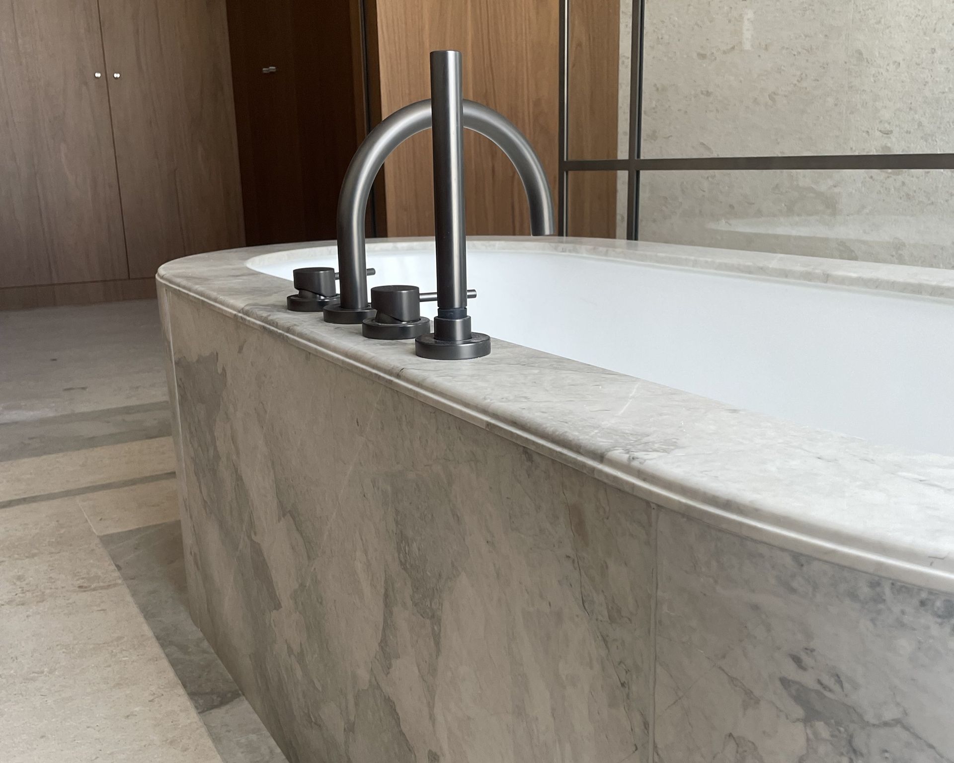 Baignoire habillée de marbre Breccia Capraia beige, salle de bains à meuble bois clair