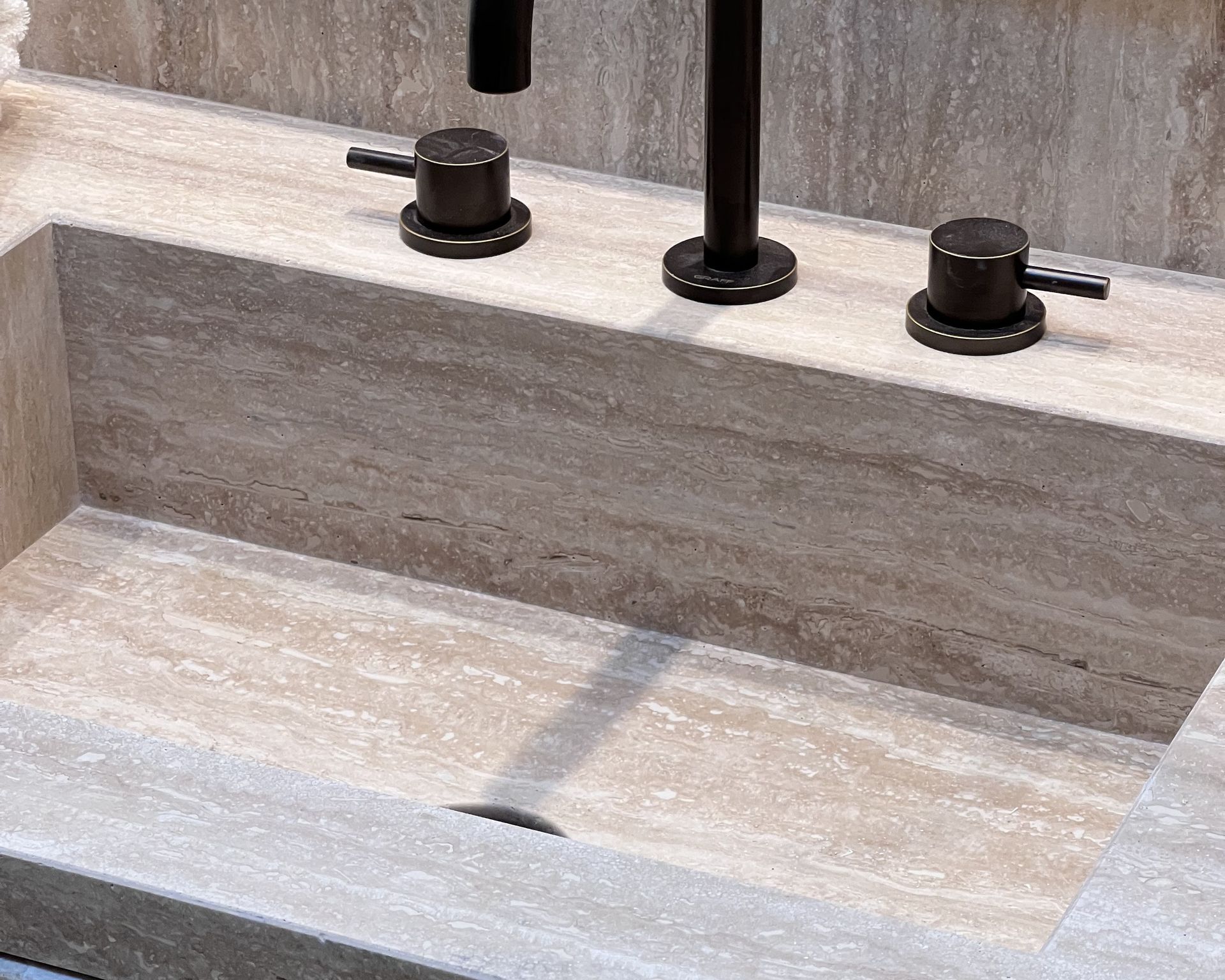 Gros plan du marbre Travertino Classique beige dans une salle de bains à meuble habillé du même marbre