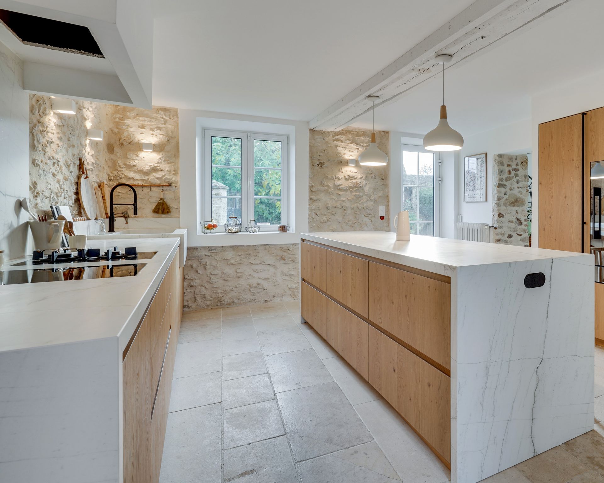Vue d'ensemble d'une cuisine à façades bois clair et plan de travail blanc en quartzite Mont Blanc